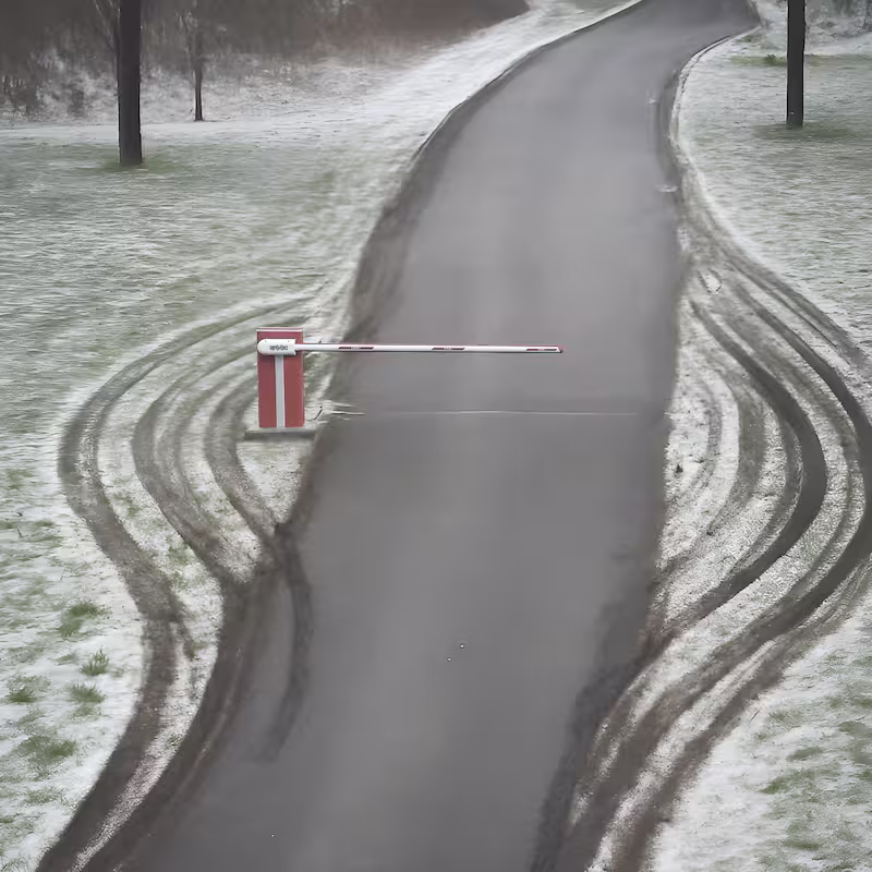 Schranke in einer Wiese mit seitlichen Fahrspuren
