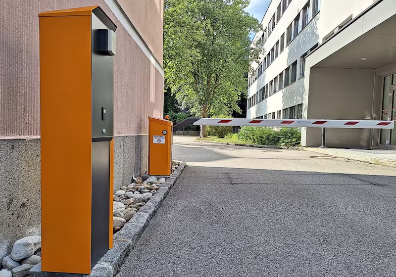 Automatische Schranke Magnetic Access an einer Parkplatzeinfahrt. Im Vordergrund steht eine Bediensäule Terminal.